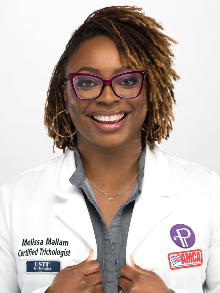 A smiling woman with glasses wearing a lab coat poses for a photo.